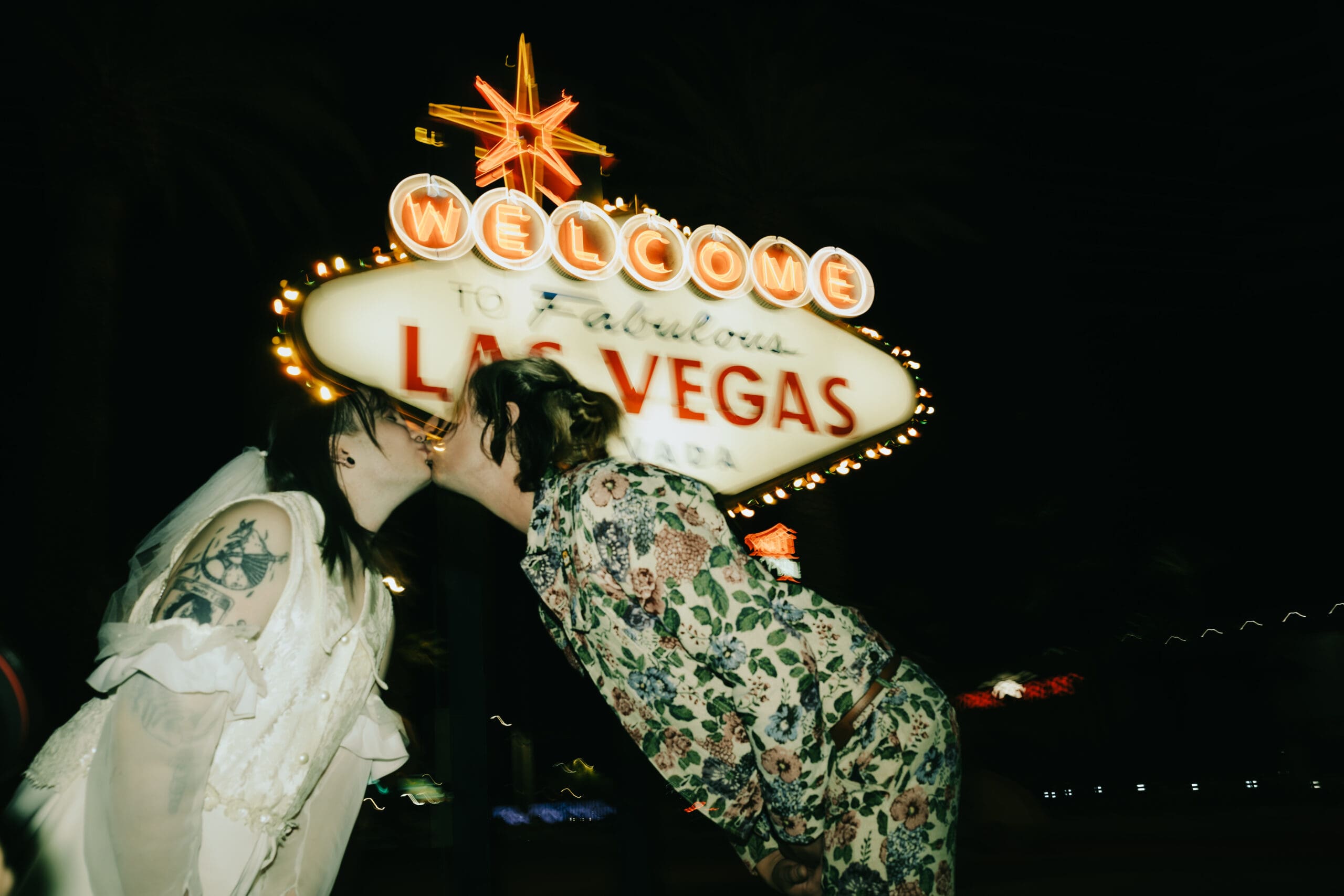 bride and groom share a kiss in front of the famous Las Vegas sign