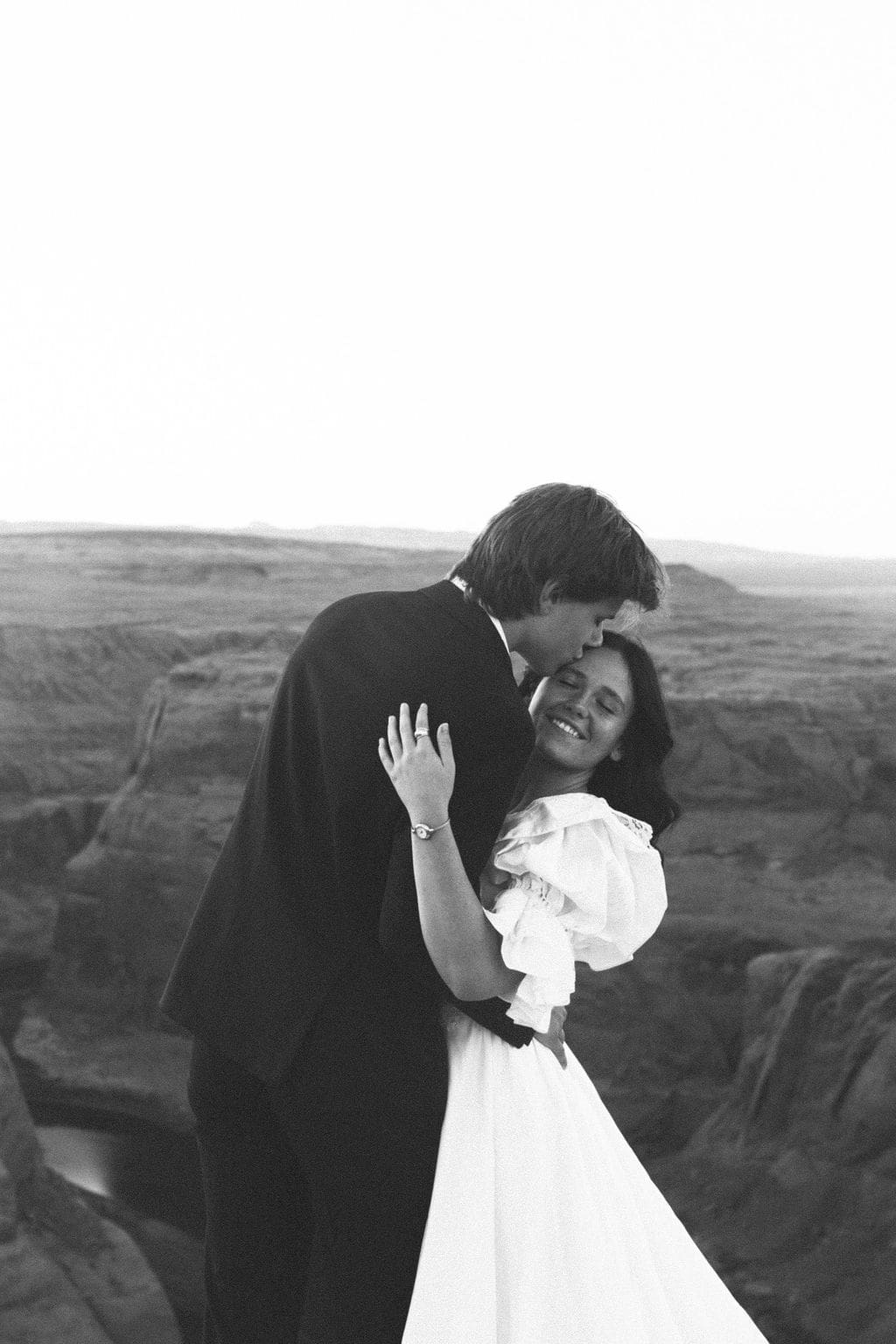 bride and groom share a romantic moment with the desert in the background