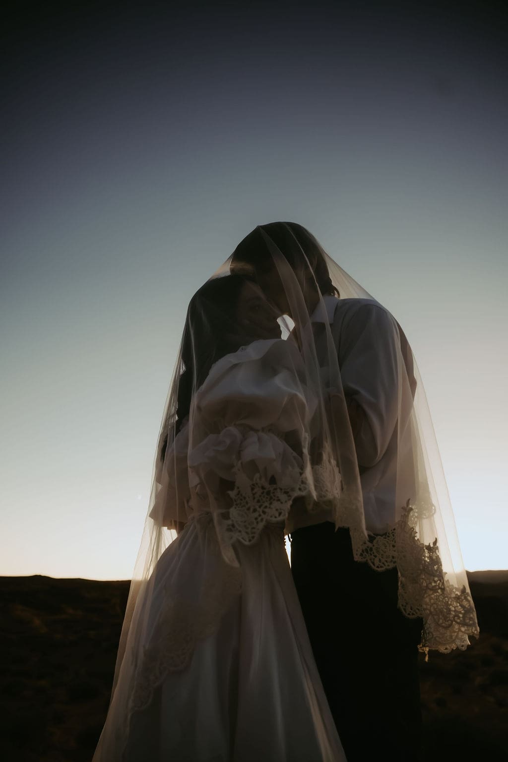 bride and groom share an intimate moment hidden by the veil