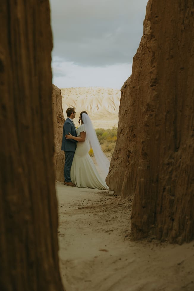 beautiful couple share an intimate moment holding each other during in the gap of the canyons during their Utah national park