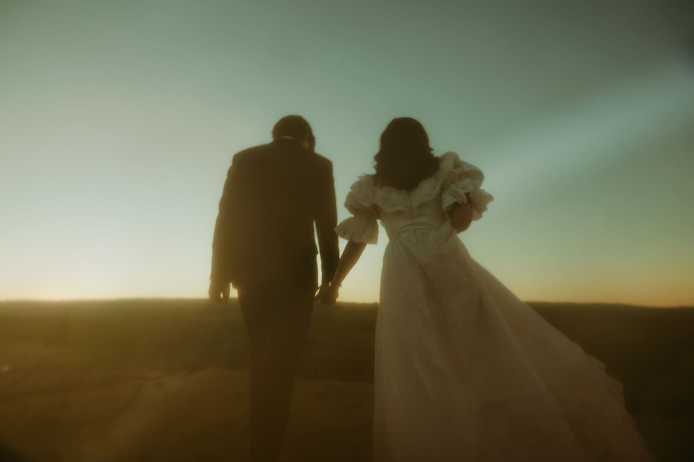 couple hold hands and walk towards the sunset during their Utah elopement day