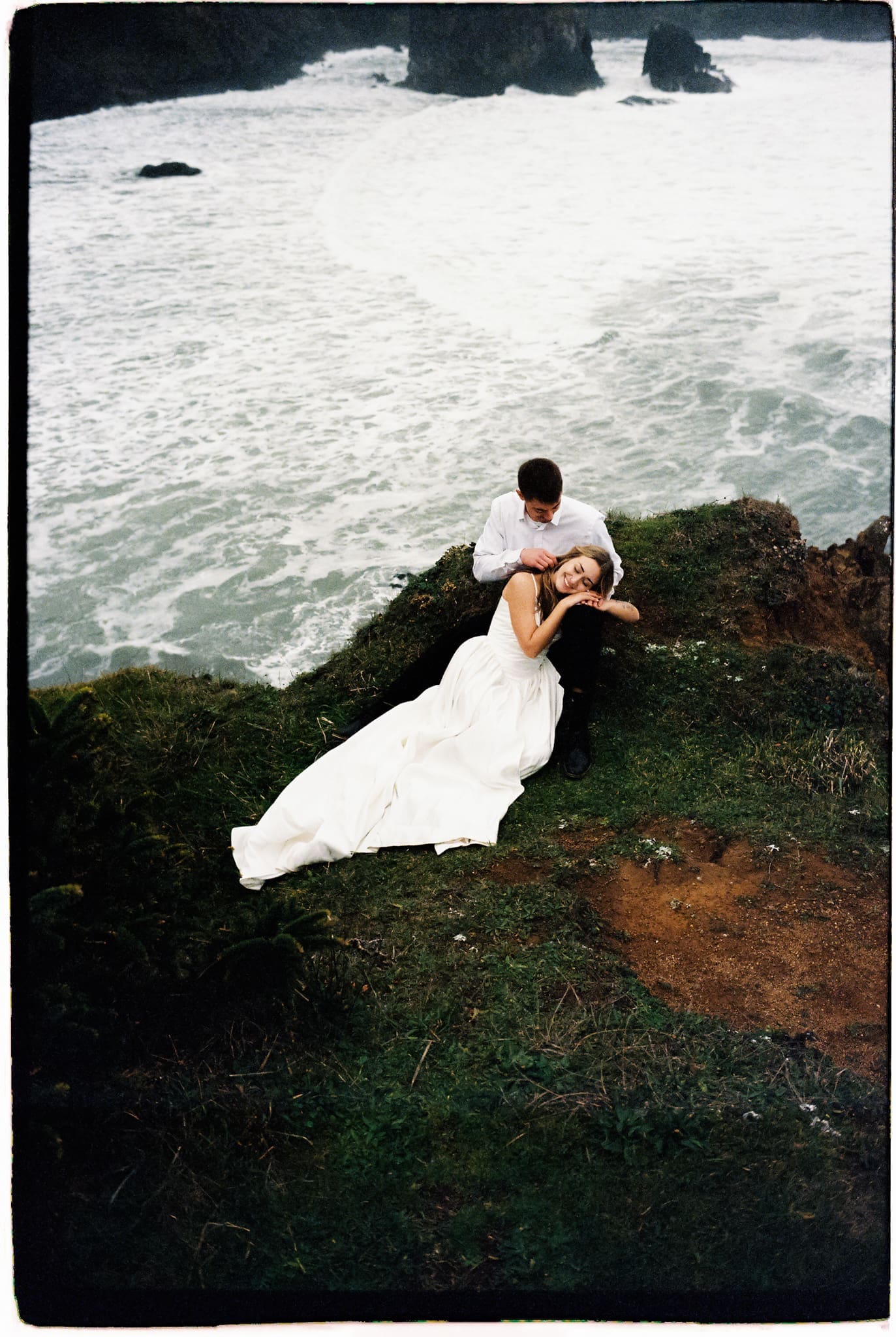 couple share an intimate moment at the edge of the pacific coast cliff