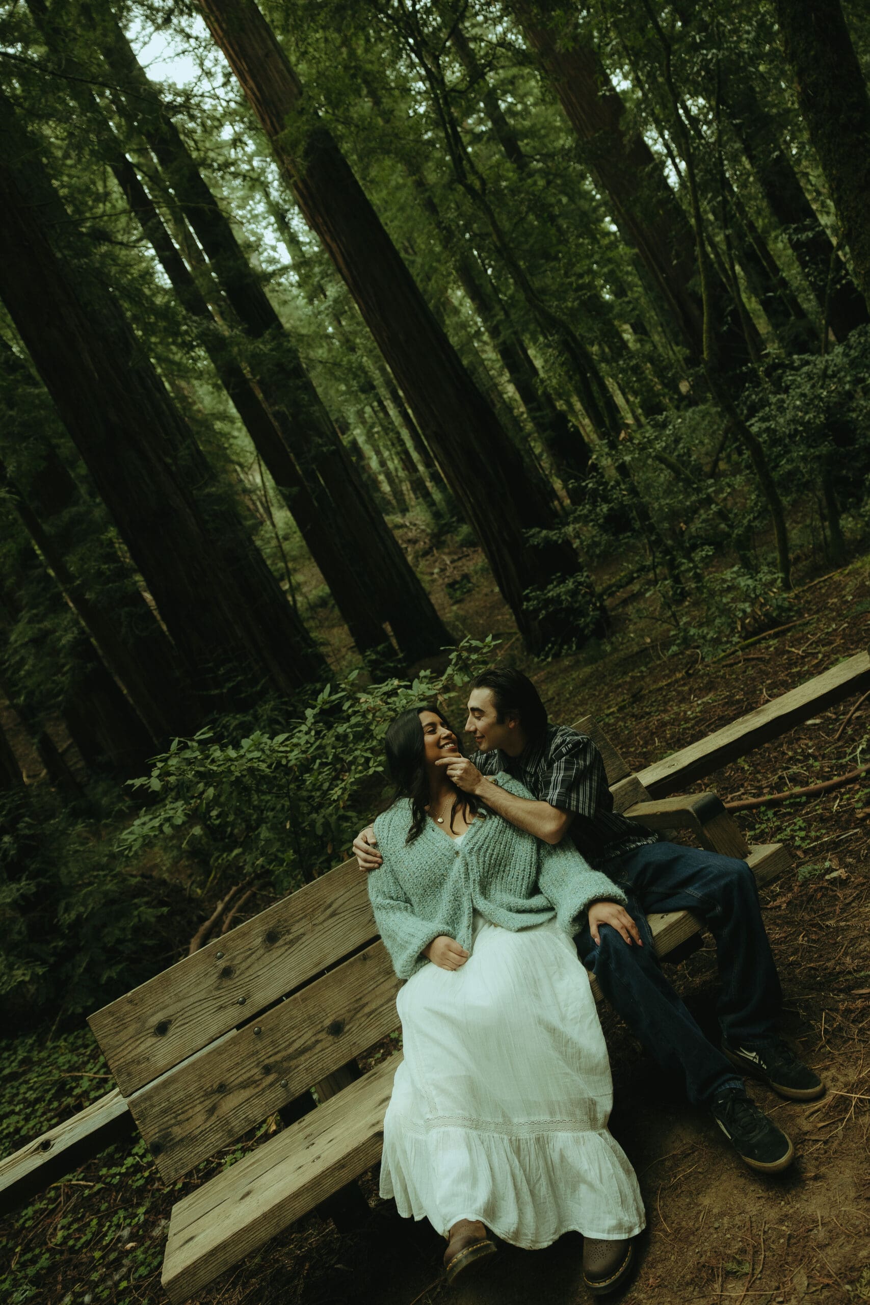 couple share a romantic moment on a bench in the forest