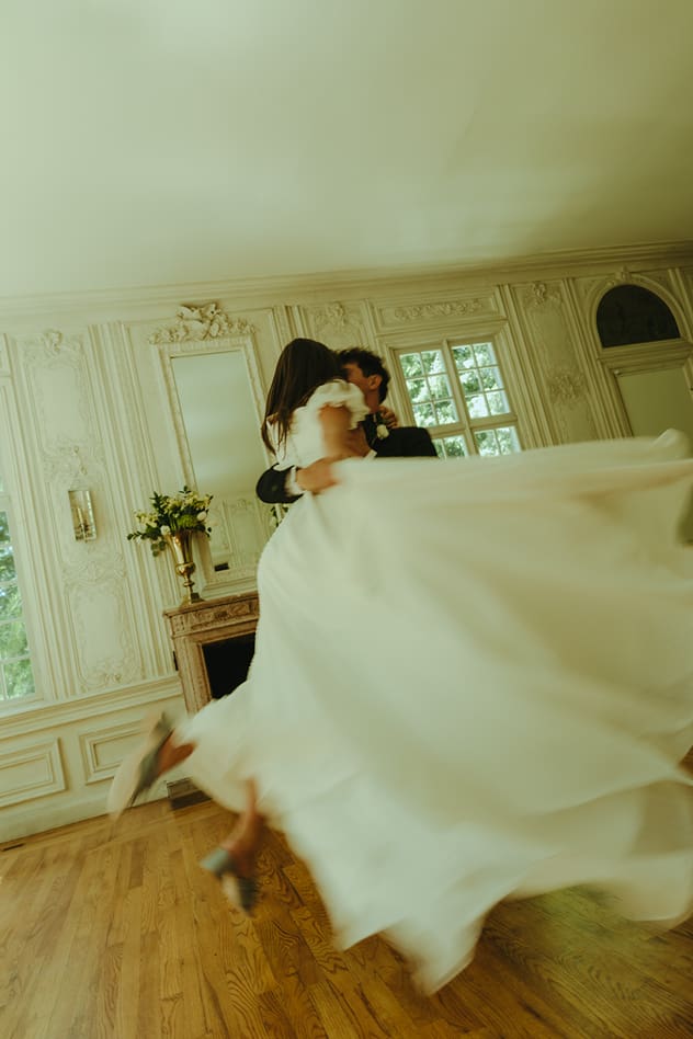 groom sweeps his bride off her feet as her dress flows around behind her